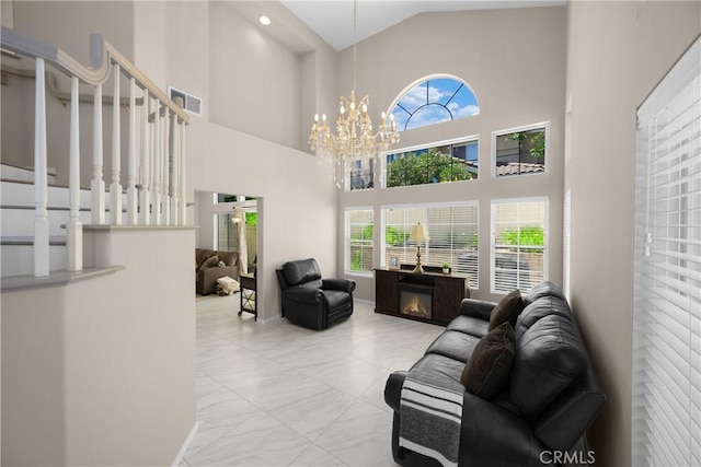 living area featuring healthy amount of natural light, a chandelier, high vaulted ceiling, stairway, and marble finish flooring