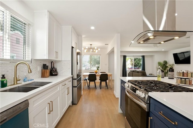 6916 Etiwanda Ave, Reseda, CA 91335 - kitchen featuring stainless steel appliances, a sink, island range hood, white cabinetry, and light wood-type flooring