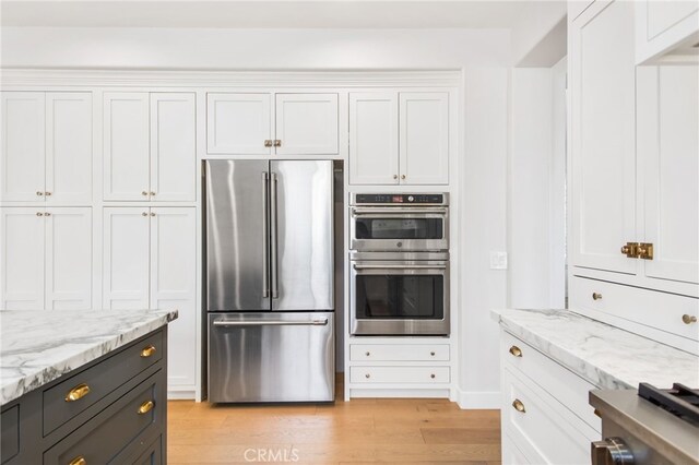 35987 Corte Renata, Murrieta, CA 92562 - kitchen featuring appliances with stainless steel finishes, white cabinetry, light wood-style floors, and light stone counters