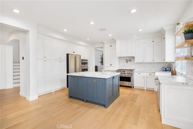 35987 Corte Renata, Murrieta, CA 92562 - kitchen with appliances with stainless steel finishes, a sink, white cabinets, arched walkways, and light wood finished floors