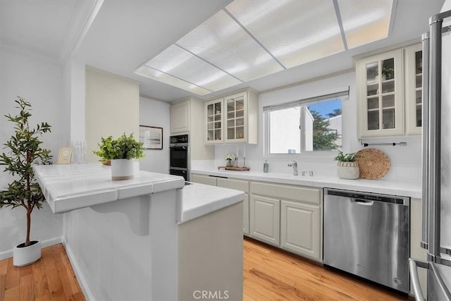 1006 Palm Ln, Redondo Beach, CA 90278 - kitchen with stainless steel dishwasher, crown molding, light wood-style flooring, a sink, and a peninsula