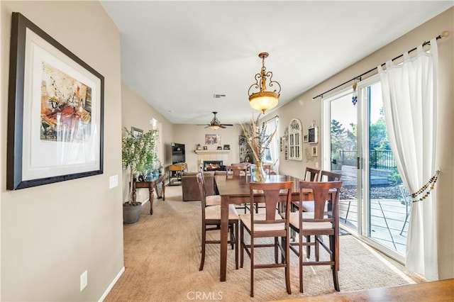 29288 Woodlea Ln, Menifee, CA 92584 - dining area featuring a lit fireplace, ceiling fan, baseboards, and light carpet