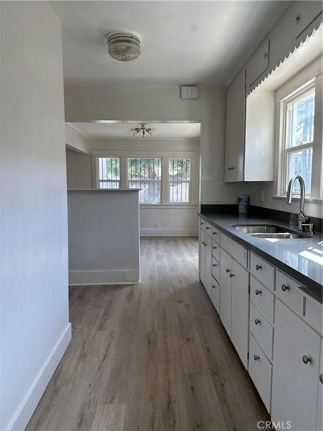 1073 Orizaba Ave, Long Beach, CA 90804 - kitchen with a sink, baseboards, dark countertops, wood finished floors, and white cabinets