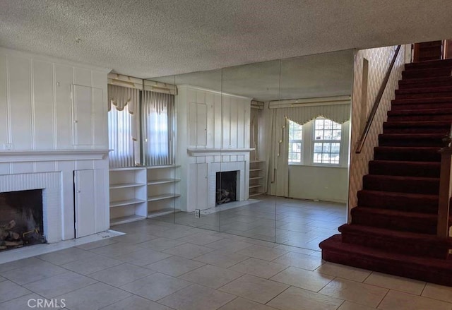 332 W Laurel, Compton, CA 90220 - unfurnished living room featuring a brick fireplace, stairs, a textured ceiling, and light tile patterned flooring