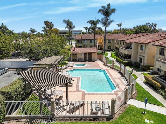 community pool featuring fence, a patio, and a hot tub
