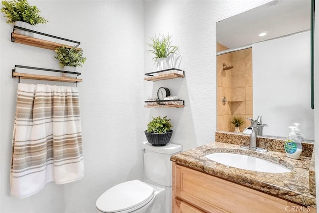 full bathroom with toilet, vanity, a shower, and a textured wall