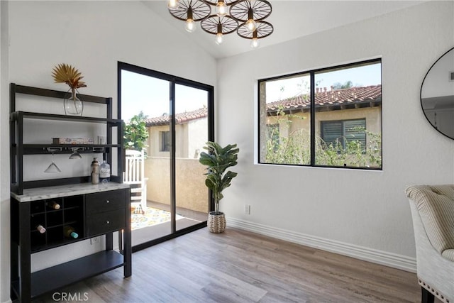 office with lofted ceiling, healthy amount of natural light, a chandelier, baseboards, and wood finished floors
