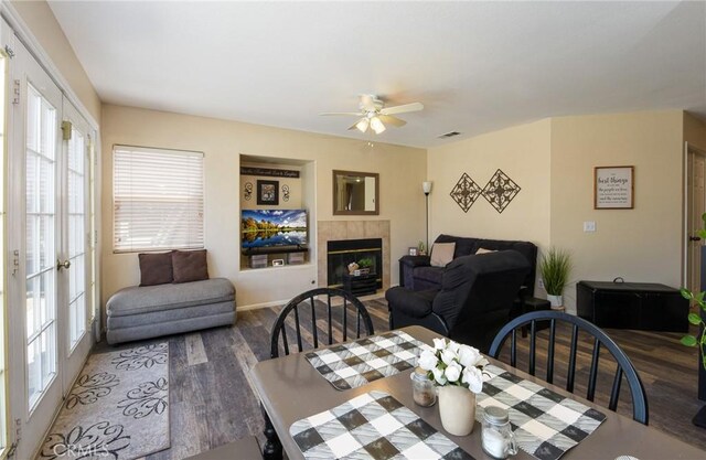 1065 Sycamore Ln, San Jacinto, CA 92582 - dining space featuring wood finished floors, a ceiling fan, a tiled fireplace, and baseboards