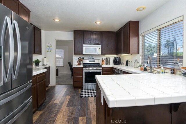 1065 Sycamore Ln, San Jacinto, CA 92582 - kitchen with appliances with stainless steel finishes, dark wood-style floors, dark brown cabinetry, recessed lighting, and a peninsula