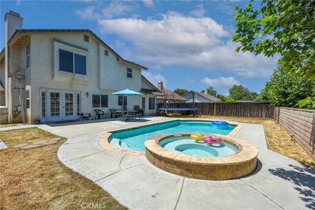 1065 Sycamore Ln, San Jacinto, CA 92582 - view of pool with french doors, a patio area, a fenced backyard, a trampoline, and a pool with connected hot tub
