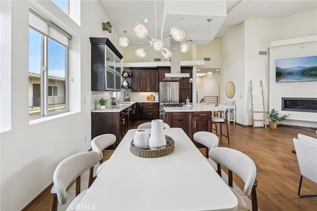 2205 Rockefeller Ln Unit B, Redondo Beach, CA 90278 - dining area featuring a towering ceiling, dark wood-style flooring, a chandelier, and baseboards