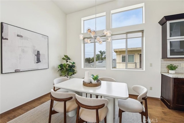 2205 Rockefeller Ln Unit B, Redondo Beach, CA 90278 - dining room featuring a chandelier, wood finished floors, baseboards, and a towering ceiling
