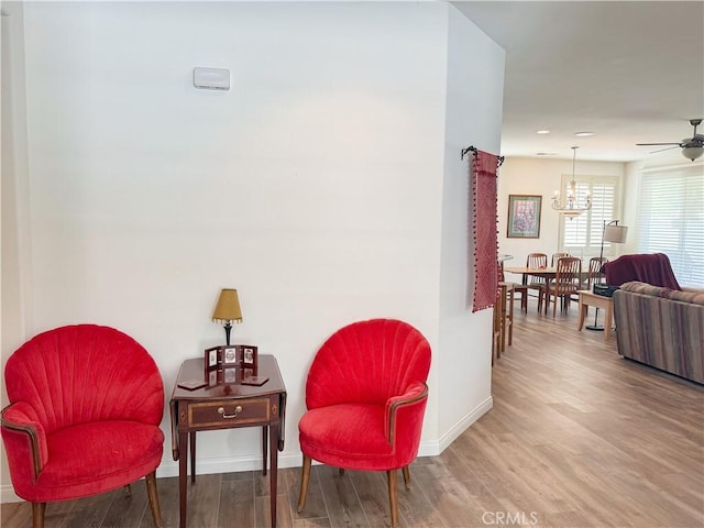 sitting room with baseboards, wood finished floors, a chandelier, a ceiling fan, and recessed lighting