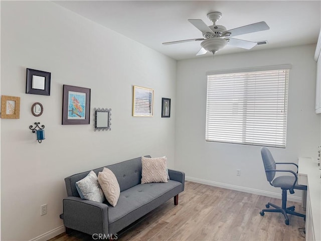 office space with a ceiling fan, baseboards, and light wood-style floors