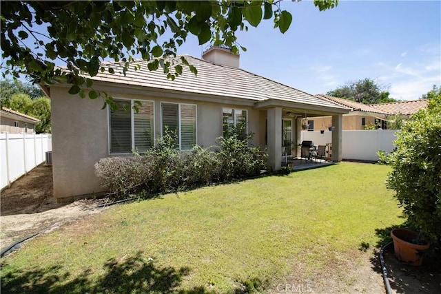 rear view of property featuring stucco siding, a chimney, a patio area, and a tile roof