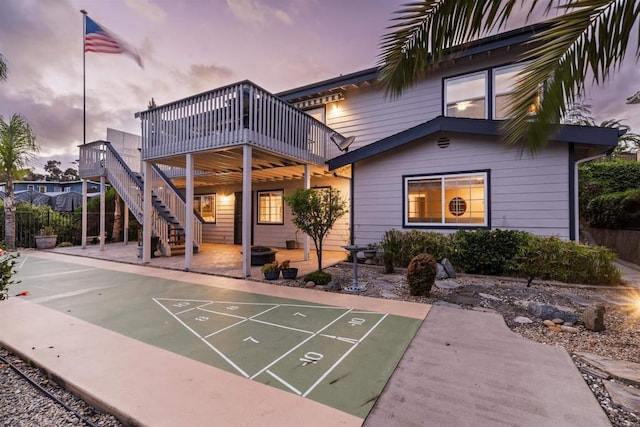 surrounding community featuring shuffleboard, a wooden deck, fence, stairs, and a patio
