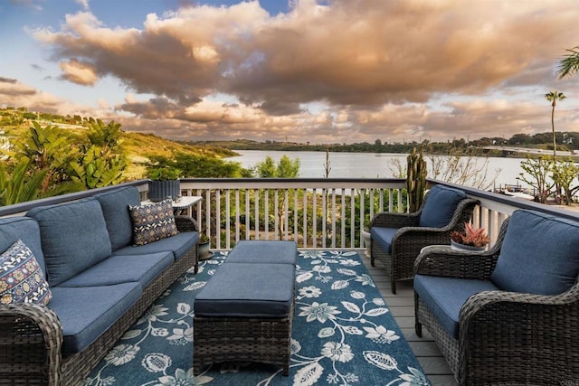 deck at dusk featuring a water view and an outdoor living space