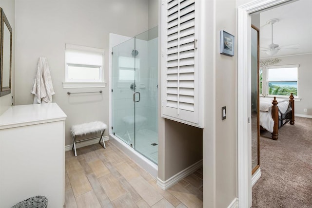ensuite bathroom featuring baseboards, ceiling fan, plenty of natural light, and a stall shower