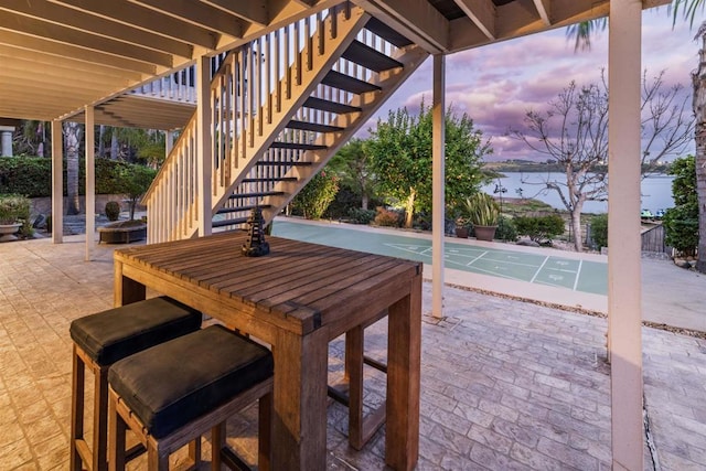 view of patio / terrace with shuffleboard, stairway, and a water view