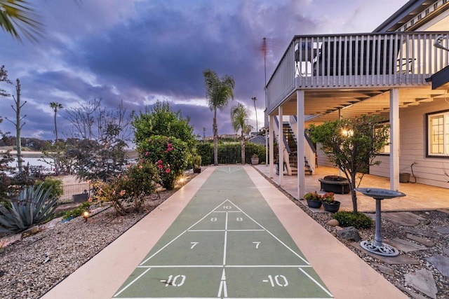 view of property's community with shuffleboard, stairway, a deck, a fire pit, and fence