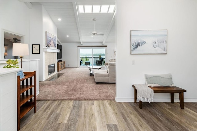 living room with ceiling fan, wood finished floors, baseboards, and a fireplace with flush hearth