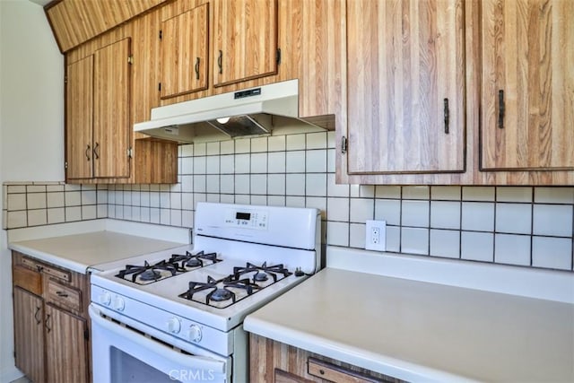 kitchen featuring gas range gas stove, under cabinet range hood, light countertops, brown cabinetry, and tasteful backsplash