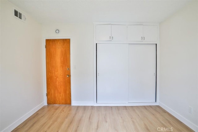 unfurnished bedroom featuring baseboards, light wood-style flooring, and a closet