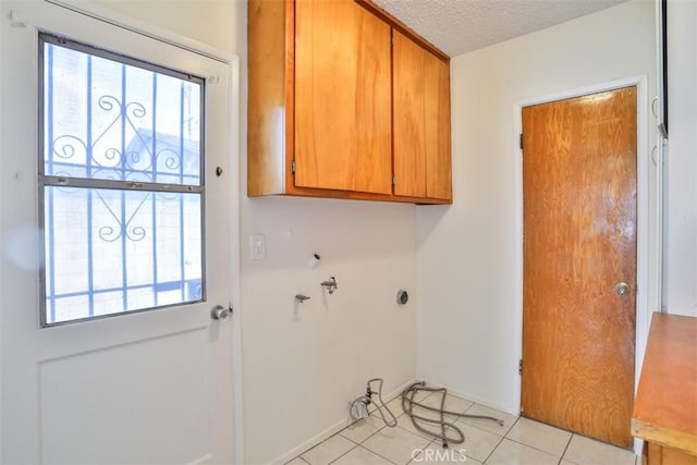 clothes washing area with cabinet space, a textured ceiling, light tile patterned floors, and baseboards