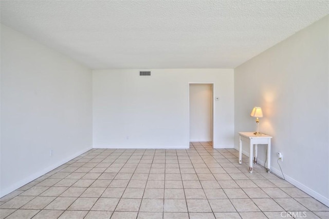 spare room with a textured ceiling, baseboards, and light tile patterned floors
