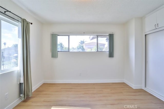 unfurnished bedroom with light wood-type flooring, baseboards, and a closet