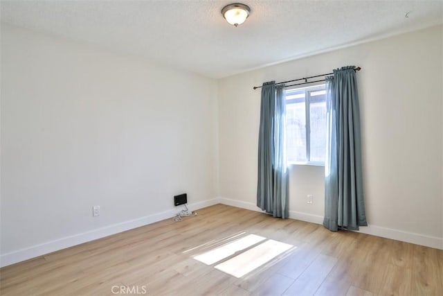 unfurnished room with wood finished floors, a textured ceiling, and baseboards
