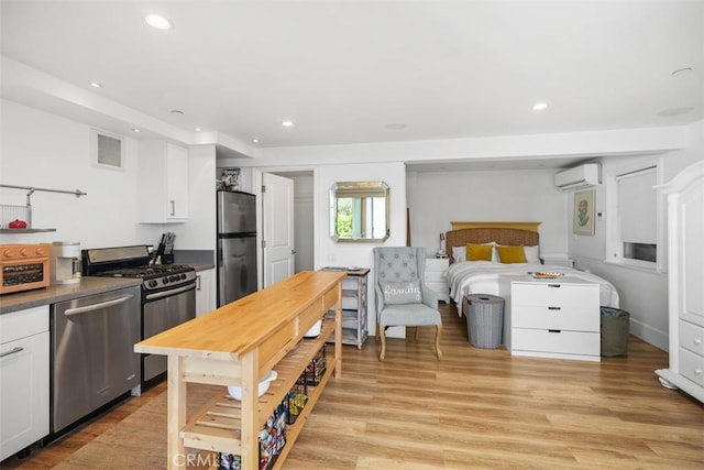 385 Mermaid, Laguna Beach, CA 92651 - kitchen with appliances with stainless steel finishes, an AC wall unit, white cabinetry, recessed lighting, and light wood-type flooring