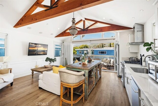 385 Mermaid, Laguna Beach, CA 92651 - kitchen featuring wall chimney exhaust hood, appliances with stainless steel finishes, beamed ceiling, wood finished floors, and high vaulted ceiling