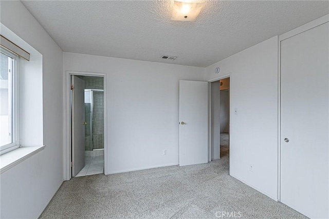1012 W Lime Ave, Lompoc, CA 93436 - unfurnished bedroom featuring multiple windows, carpet, a textured ceiling, and ensuite bathroom