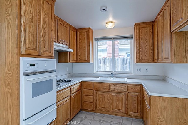 1012 W Lime Ave, Lompoc, CA 93436 - kitchen with a sink, white oven, gas cooktop, brown cabinets, and under cabinet range hood