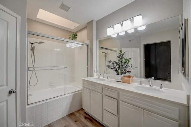 2643 Dietrich Dr, Tustin, CA 92782 - bathroom featuring tiled shower / bath, a skylight, wood finished floors, and double vanity