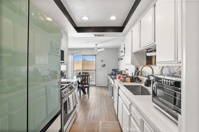 21814 Belshire Ave Unit 2, Hawaiian Gardens, CA 90716 - kitchen with gas range, a sink, a tray ceiling, refrigerator, and white cabinets