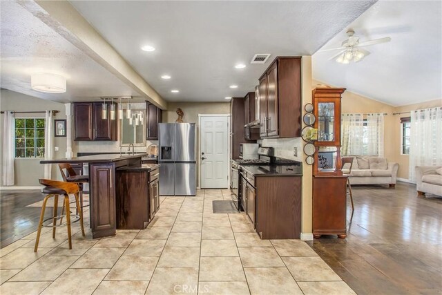 11425 Bryant St, Yucaipa, CA 92399 - kitchen with stainless steel appliances, dark countertops, a breakfast bar, plenty of natural light, and recessed lighting