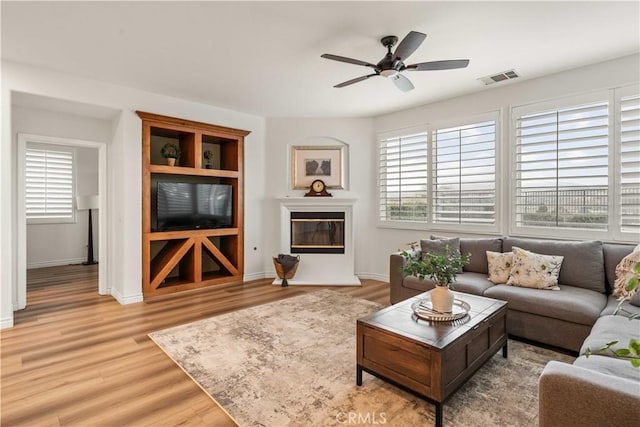 23911 Brio Ct, Valencia, CA 91354 - living room with light wood-type flooring, a ceiling fan, baseboards, and a glass covered fireplace