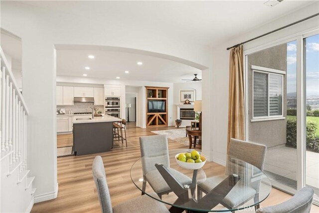 23911 Brio Ct, Valencia, CA 91354 - dining room with a ceiling fan, light wood finished floors, arched walkways, recessed lighting, and stairs
