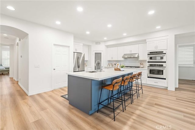 23911 Brio Ct, Valencia, CA 91354 - kitchen with appliances with stainless steel finishes, under cabinet range hood, a sink, a kitchen bar, and recessed lighting