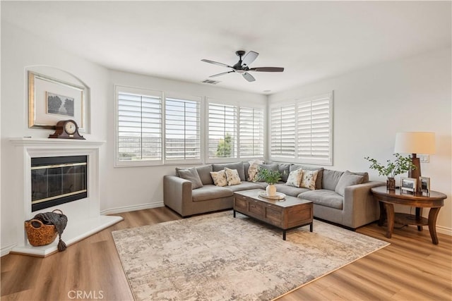 23911 Brio Ct, Valencia, CA 91354 - living area with ceiling fan, light wood-style floors, a glass covered fireplace, and baseboards