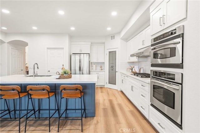23911 Brio Ct, Valencia, CA 91354 - kitchen with appliances with stainless steel finishes, under cabinet range hood, a sink, a kitchen bar, and recessed lighting
