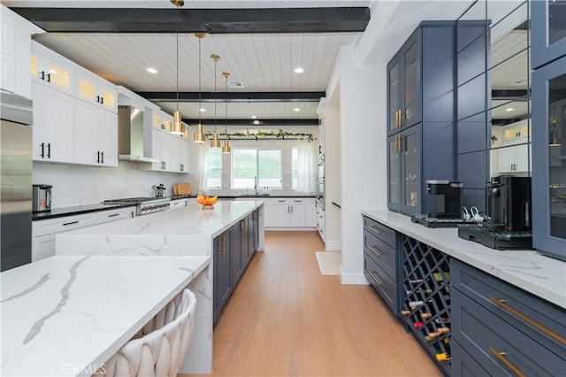 451 Avenida Esplendor, Walnut, CA 91789 - kitchen featuring wall chimney range hood, light wood-style floors, beam ceiling, a sink, and white cabinetry