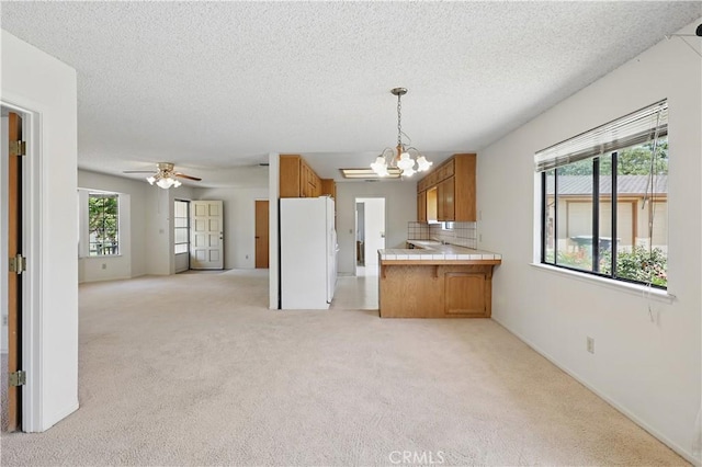 442 R St, Merced, CA 95341 - kitchen with freestanding refrigerator, brown cabinets, tile countertops, open floor plan, and light colored carpet