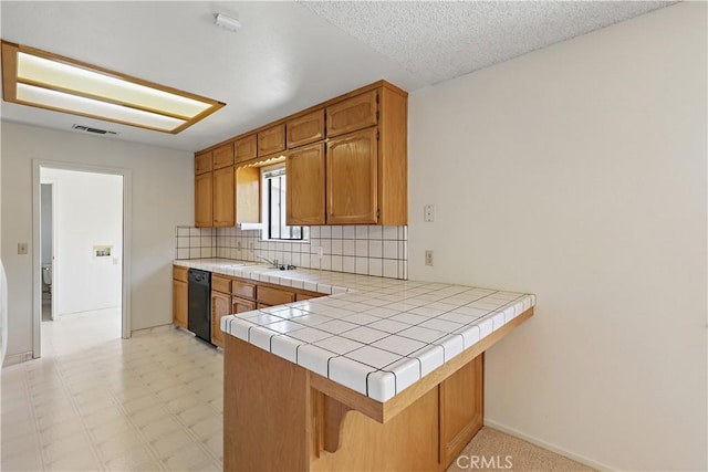 442 R St, Merced, CA 95341 - kitchen featuring dishwasher, decorative backsplash, tile counters, brown cabinetry, and a peninsula