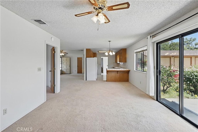 442 R St, Merced, CA 95341 - kitchen with brown cabinetry, freestanding refrigerator, ceiling fan, light carpet, and a chandelier