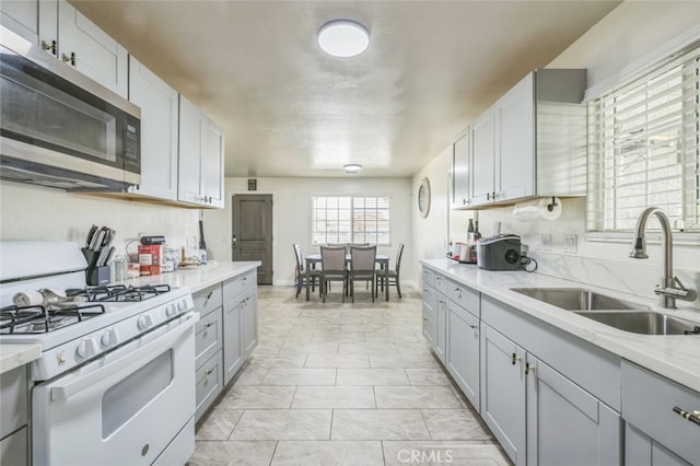 15025 Avenida Ramada, Desert Hot Springs, CA 92240 - kitchen with white gas range, a sink, stainless steel microwave, gray cabinetry, and light stone countertops