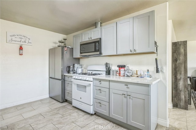 15025 Avenida Ramada, Desert Hot Springs, CA 92240 - kitchen featuring stainless steel appliances, gray cabinets, light countertops, and baseboards