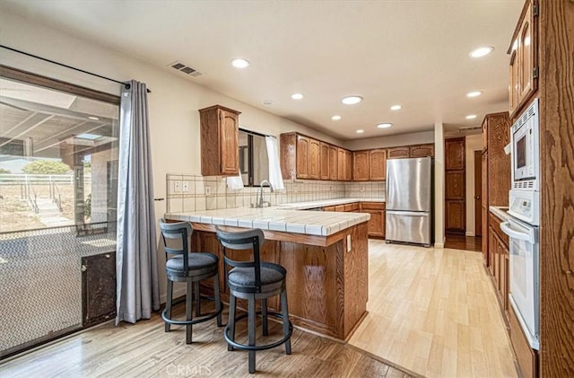 420 Via Vicente, Nipomo, CA 93444 - kitchen with white appliances, a peninsula, light wood finished floors, recessed lighting, and backsplash